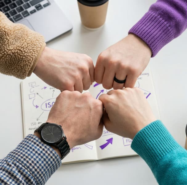 Quatre poings qui se rejoignent au-dessus d'un carnet de schémas